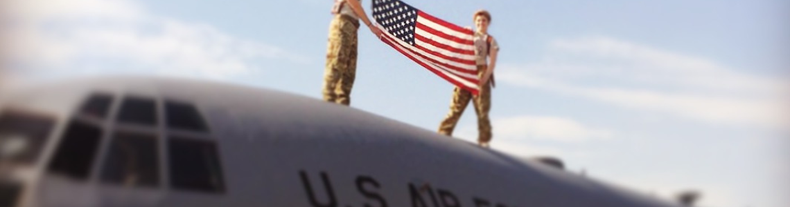 1L and Air Force Veteran Emily Elmore (left) holds an American flag on top of an Air Force plane.