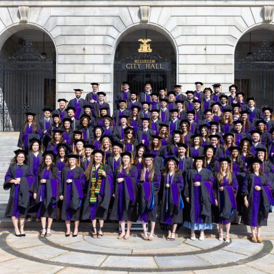 Photo of the entire Class of 2026 on the steps of city hall in their robes and hats.