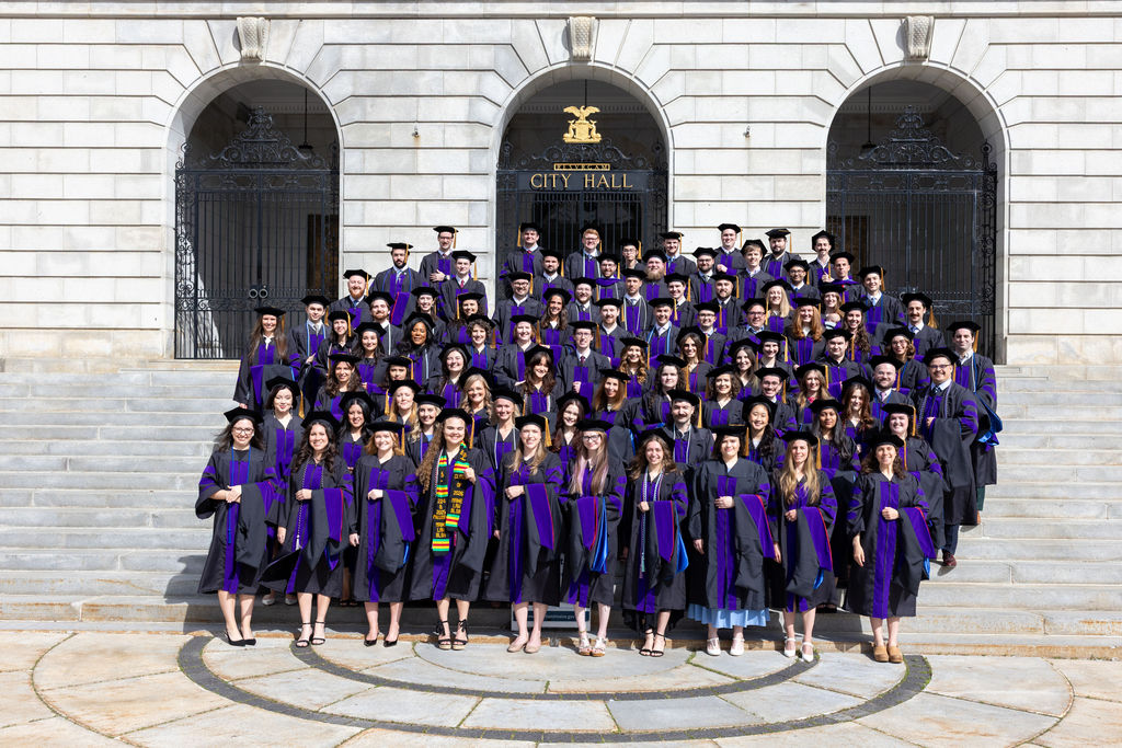 Photo of the entire Class of 2026 on the steps of city hall in their robes and hats.