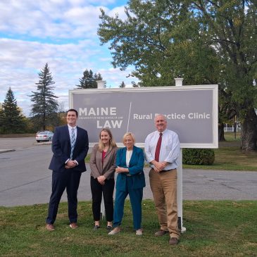 A photo of four individuals standing in front of a sign that reads "Rural Practice Clinic.