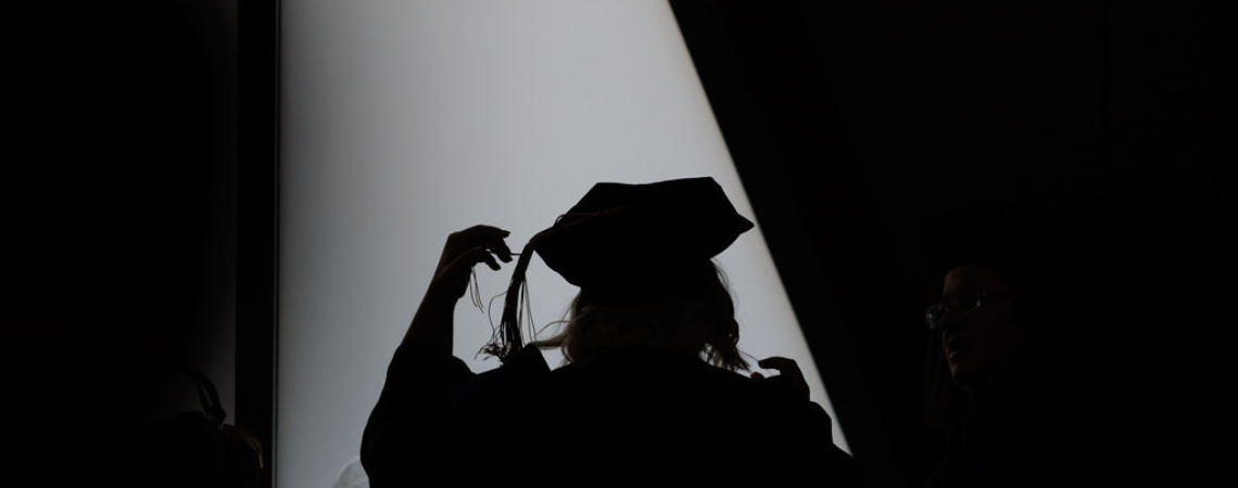 Black and white photo of a woman moving the tassel on her graduation cap