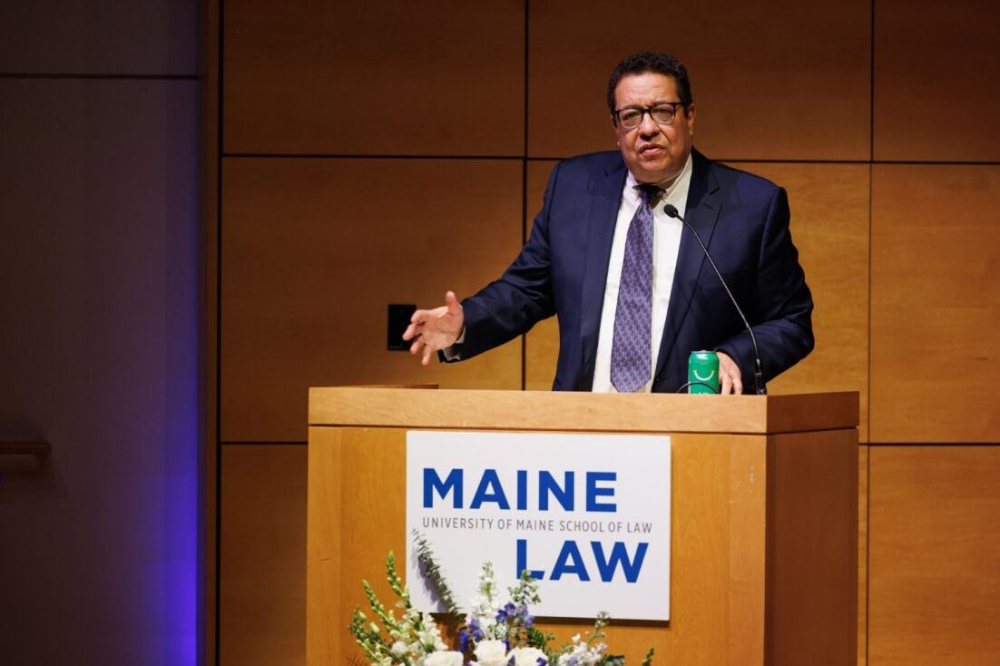Dennis Parker lecturing at podium with Maine Law signage 