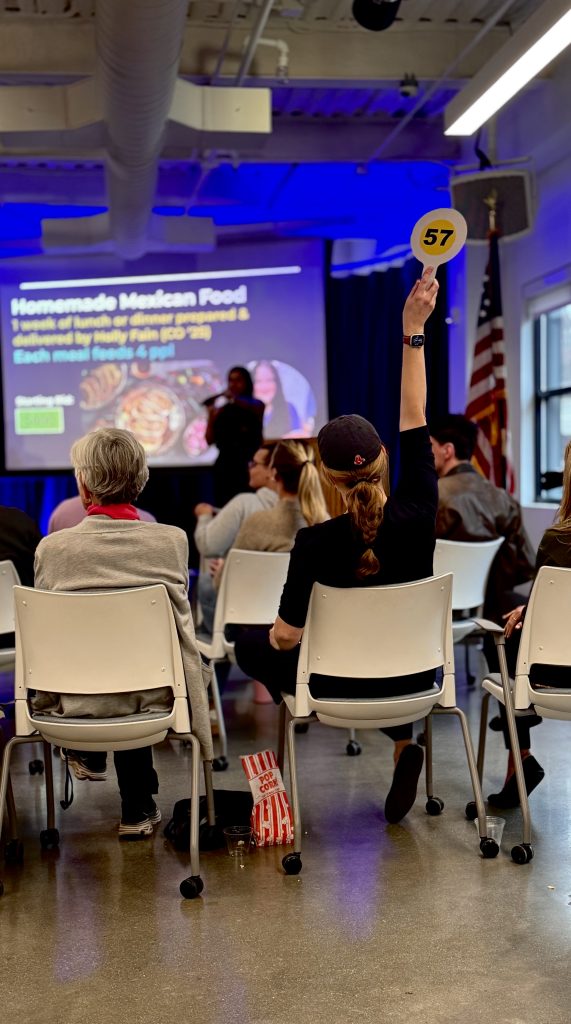 Someone raises an auction paddle in the Maine Law living room.