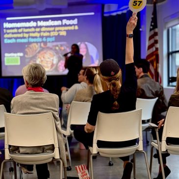 Someone raises an auction paddle in the Maine Law living room.