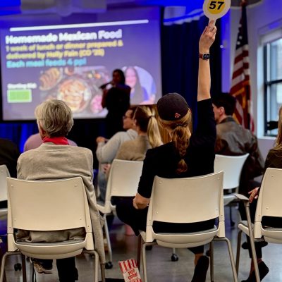 Someone raises an auction paddle in the Maine Law living room.