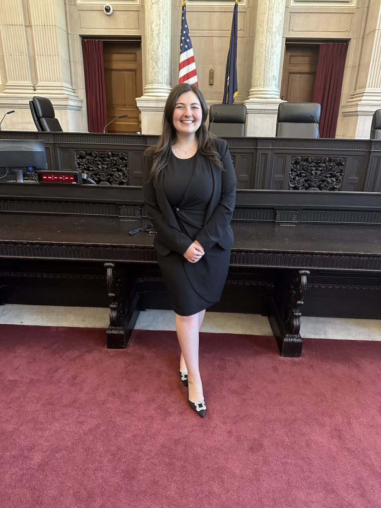 Photo of a woman standing in front of the judges bench in a courtroom.
