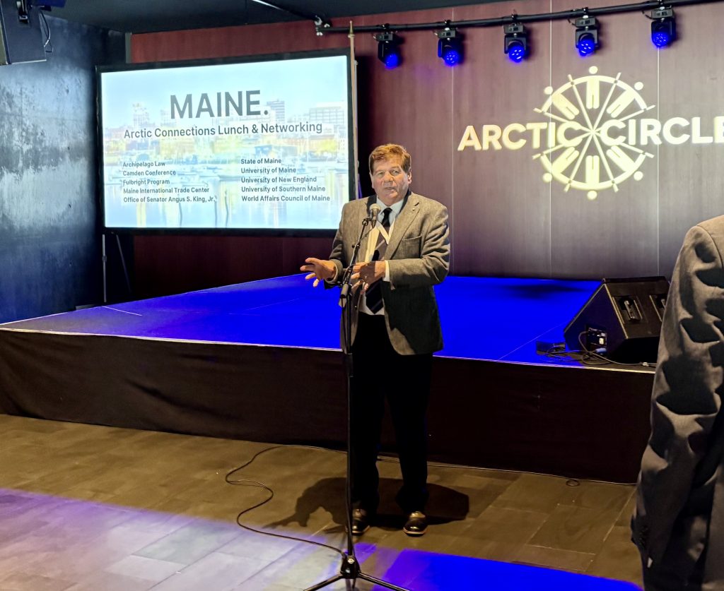 Professor Norchi presenting at Arctic Law Assembly, standing in front of a PowerPoint screen that says "Maine."