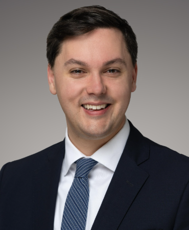 Headshot of Adam in a suite and tie